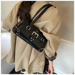 Detail of black punk shoulder bag with silver studs and a large buckle on model