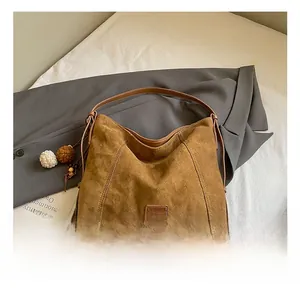 Detail of a brown suede hobo bag with plush charm on a gray blazer setting