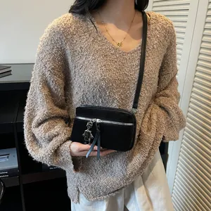 Elegant black suede mini crossbody bag with a robot charm and silver hardware on model