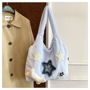 Detailed shot of plush blue tote bag with star patches and bone pendant decoration