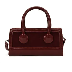 Chic burgundy handbag with mixed suede and glossy leather textures in a sleek rectangular shape