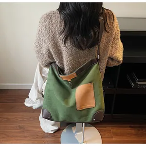 Detail of green canvas tote with brown leather trim and metal rivets shown on model