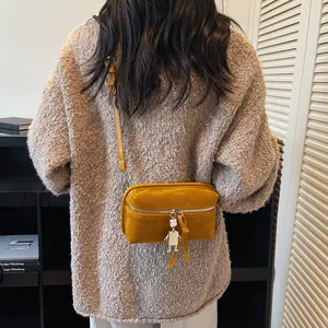 Chic mustard yellow suede crossbody box bag with metal robot charm on beige sweater