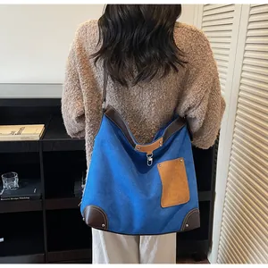 Rear view of model wearing a large blue suede tote bag with brown leather contrast trim