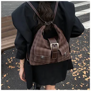 Detailed view of a vintage brown plaid backpack with front flap pockets and turn-lock closures