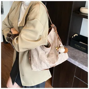 Detail of soft khaki suede tote bag with boho tassel pendant and decorative stitching