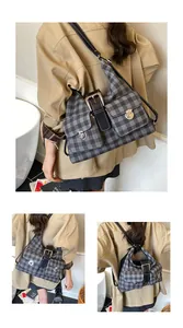 Detail of grey plaid shoulder bag with vintage buckles and dual front flap pockets