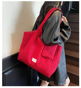 Détail du sac cabas rouge en toile plissée montrant le tissu texturé et le petit porte-monnaie