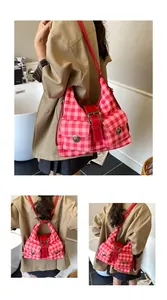 Detail view of pink plaid shoulder bag with front double pockets and red strap buckle