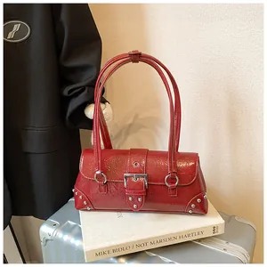 Macro shot of dark red patent leather shoulder bag with metallic buckle and stud details