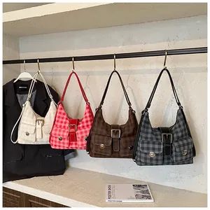 Detail view of four vintage plaid shoulder bags with dual front buckle pockets on a display