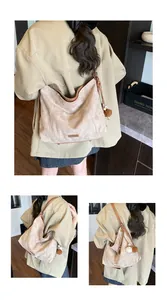 Detail of bohemian canvas hobo bag with brown leather trim and plush pom-pom charms