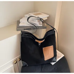 Detail of a large suede tote bag featuring black and brown contrast panels and leather corners