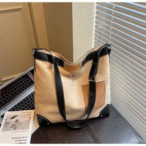 Detail of canvas tote bag with brown leather pocket, black trim, and spacious interior