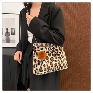 Dettaglio borsa a spalla in finta pelliccia leopardata con catena e ciondolo a pompon