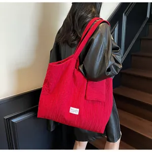 Détail du sac cabas en toile rouge avec texture plissée verticale et petite pochette assortie