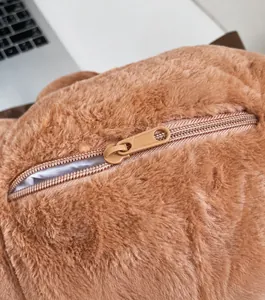 Dettaglio della cerniera scorrevole e della morbida consistenza in peluche dell'orso