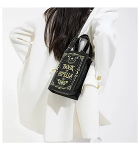 Gothic Book of Spells crossbody bag in black faux leather held by a model in white suit