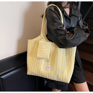 Gros plan d'un sac cabas jaune pâle avec texture gaufrée et une petite pochette