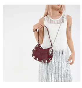 Detailed macro view of dark red patent leather crescent bag with silver stud trim