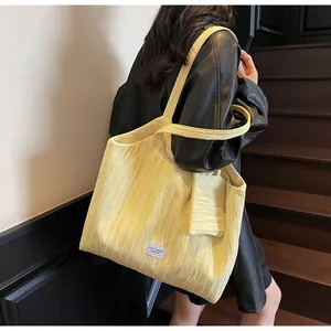 Détail du sac fourre-tout jaune plissé avec une mini pochette et logo étiquette