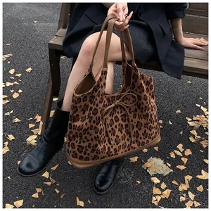 Détail du sac cabas léopard avec nœud décoratif et anses en cuir sur un banc d'automne