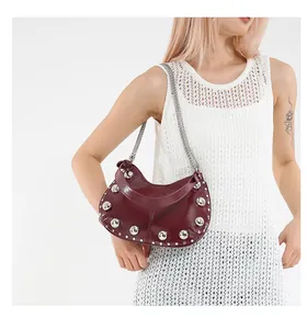 Detail of dark red studded shoulder bag with silver chain worn by a model