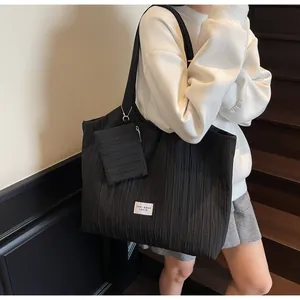 Détail du sac fourre-tout plissé noir avec pochette assortie et étiquette blanche