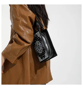Detail of black crossbody bag with white occult moon and star patterns on premium leather