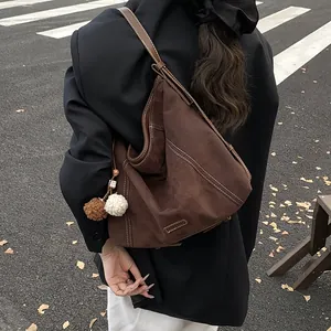 Deep brown matte tote bag with contrast stitching and plush charm shown on street
