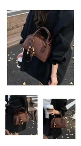 Detail of a brown suede Boston bag with wooden bead fringe and gold hardware in street style