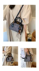 Close-up of retro color-block shell bag with suede finish and ethnic tassel charm