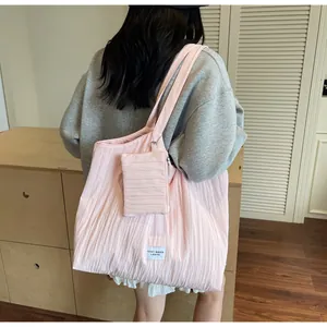 Détail du sac fourre-tout en toile plissée rose avec petit porte-monnaie et étiquette logo