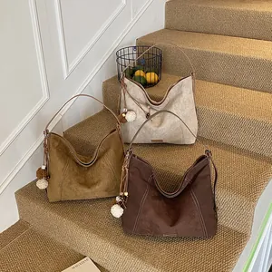 Three minimalist large hobo bags in beige, camel, and dark brown with stitching and charms