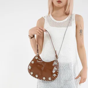 Brown half-moon underarm bag with silver rivets and metal chain shown on model