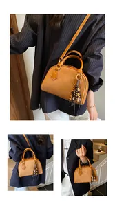 Close-up of vintage brown shell bag showing suede texture and wooden bead tassel details