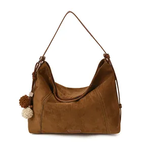 Brown soft suede hobo shoulder bag with plush pompom charm in minimalist design