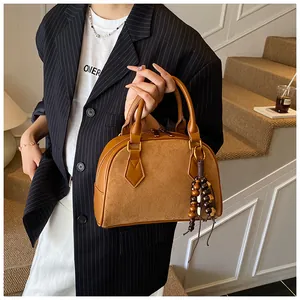 Detail of a brown vintage leather handbag with suede patchwork and colorful bead charm