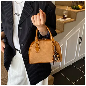 Close-up of brown suede and leather shell bag with vintage wooden bead tassel detail