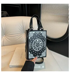 Close-up of gothic book-shaped handbag with celestial moon and star print patterns