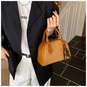Detail of brown Boston handbag with frosted leather texture and wooden bead tassel