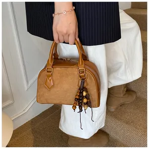 Detail of vintage brown suede satchel with wooden bead tassels held by a model