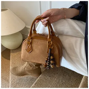 Detail of brown leather and suede shell bag with wooden bead tassel in vintage setting