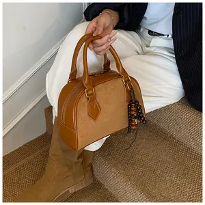 Close-up of brown patchwork Boston bag with suede texture and wooden bead charm