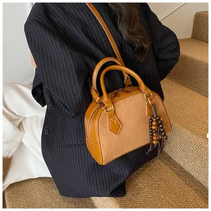 Detail of caramel leather shoulder bag featuring wood bead tassel and smooth zipper