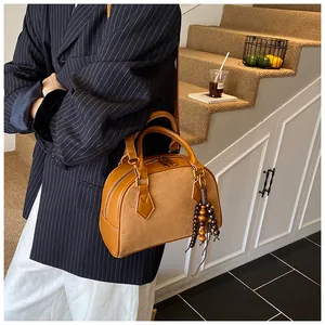 Detail of vintage brown shell bag with leather texture and stylish beaded tassel charm