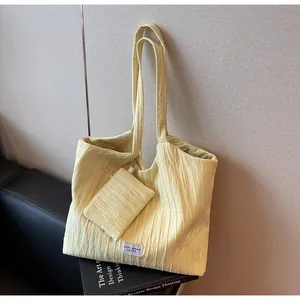 Détail du sac cabas en toile jaune clair plissée avec mini pochette assortie et bandoulière