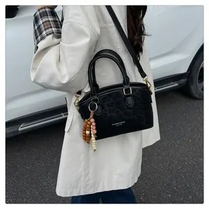 Gros plan du sac noir à texture animale avec boucles dorées et pendentif en perles
