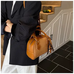 Close-up of brown Boston handbag featuring premium leather stitching and wood bead charm