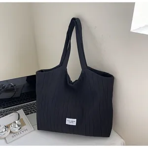 Détail d'un cabas en toile plissée noire avec étiquette sur un bureau minimaliste